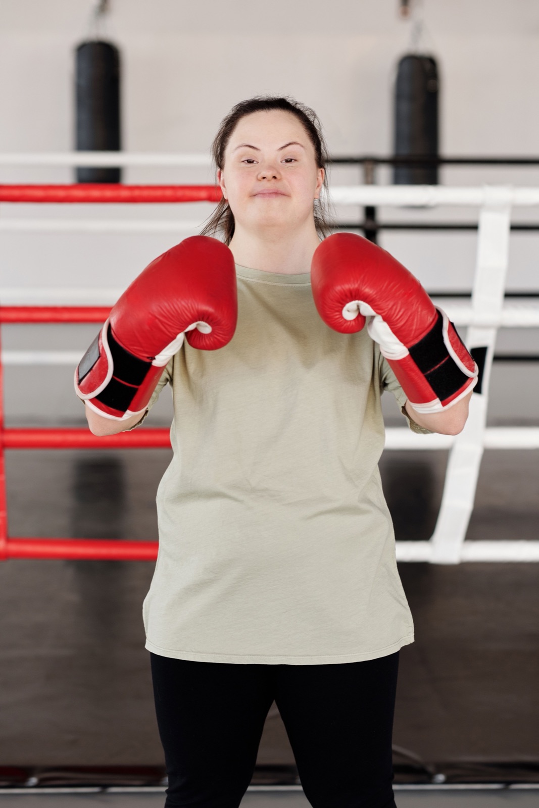 A young woman with Down syndrome wearing red boxing gloves in a boxing ring